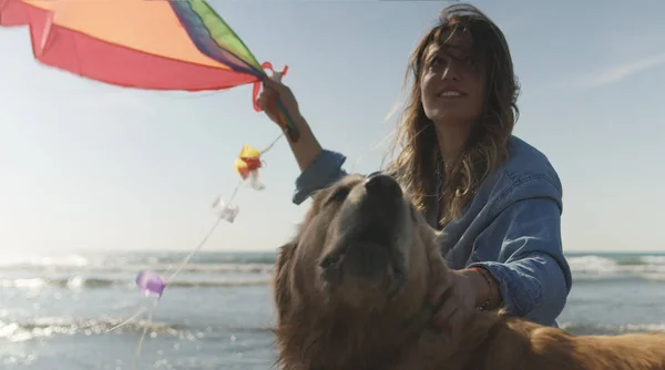 美丽的年轻女子带着狗在沙滩上抱着一只风筝 — 图库照片