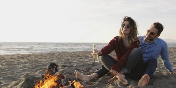 在火中放松的年轻夫妇 喝啤酒 喝水壶里的水 — 图库照片