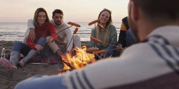 Gruppo Giovani Amici Seduti Vicino Fuoco Tarda Notte Grigliando Salsicce — Foto Stock