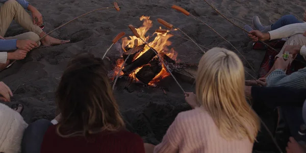 Grupo Jóvenes Amigos Sentados Junto Fuego Tarde Noche Asando Salchichas — Foto de Stock