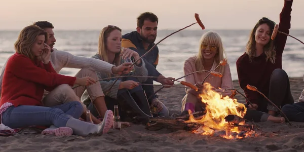 Gruppo Giovani Amici Seduti Vicino Fuoco Tarda Notte Grigliando Salsicce — Foto Stock