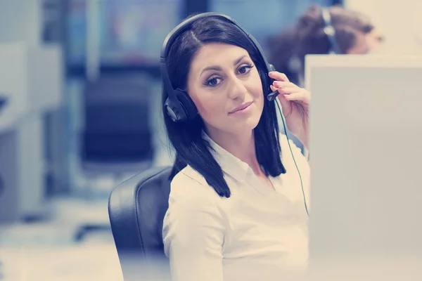 年轻微笑的女呼叫中心操作员带着耳机做她的工作 — 图库照片