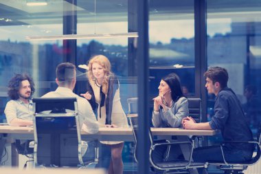 Bir grup genç iş adamı modern ofis binasında iş planlarını tartışıyor