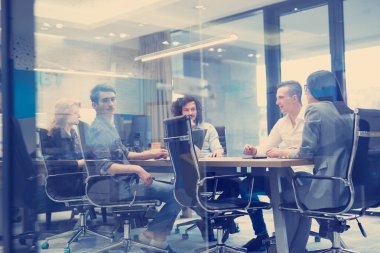 Bir grup genç iş adamı modern ofis binasında iş planlarını tartışıyor