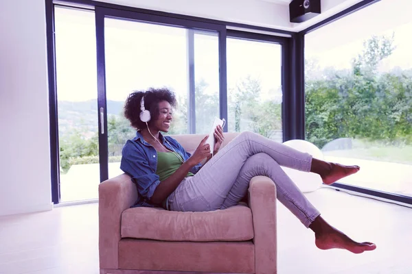 Femme afro-américaine à la maison dans une chaise avec tablette et tête pho — Photo