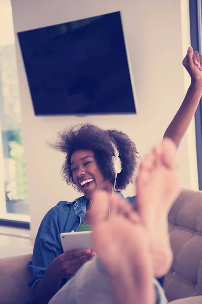 Mujer afroamericana en casa en silla con tableta y cabeza pho —  Fotos de Stock