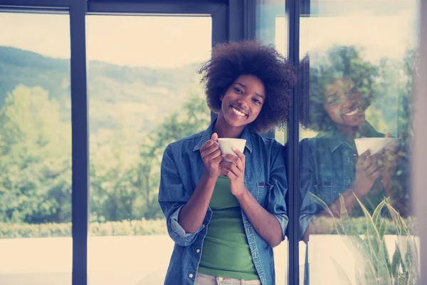 African American woman drinking coffee looking out the window