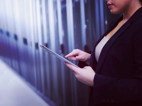 Female IT engineer working on a tablet computer in server room at modern data center