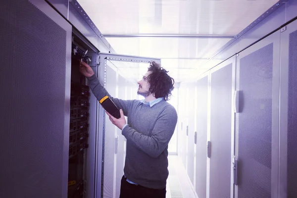 在大型数据中心服务器上使用数字电缆分析仪的年轻 技术员 — 图库照片