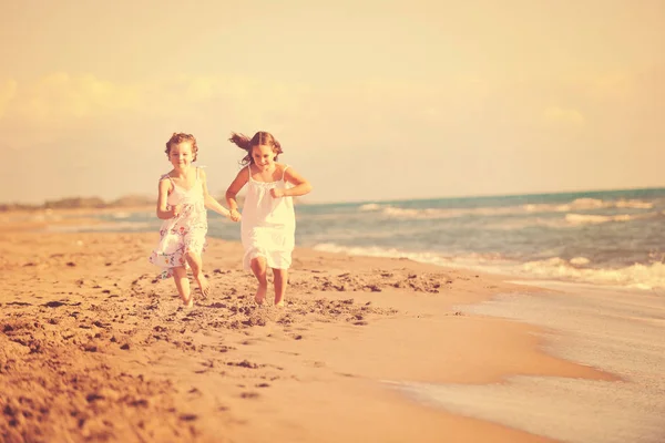 两个小女孩在美丽的海滩上欢欢喜喜地奔跑着 — 图库照片