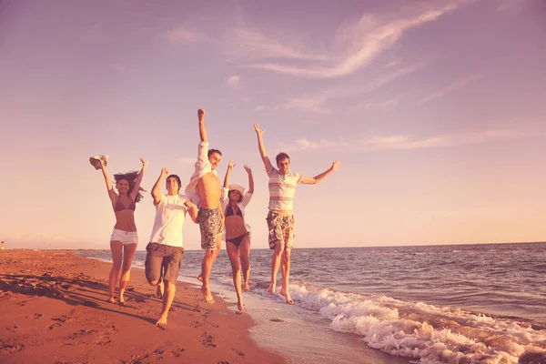 在日落时分 快乐的年轻人群在海滩上欢快地奔跑和跳跃 — 图库照片