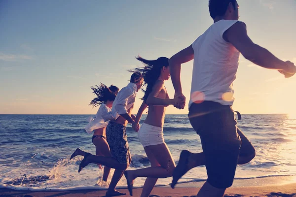Mutlu gençlik grupları gün batımında beyazlar gibi koşup zıplıyor.