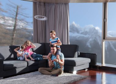 Mutlu bir aile. Baba, anne ve çocuklar video oyunu oynuyorlar. Baba ve oğul yerde oyun oynuyorlar.