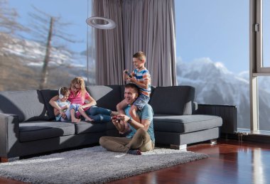 Mutlu bir aile. Baba, anne ve çocuklar video oyunu oynuyorlar. Baba ve oğul yerde oyun oynuyorlar.