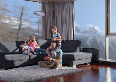 Mutlu bir aile. Baba, anne ve çocuklar video oyunu oynuyorlar. Baba ve oğul yerde oyun oynuyorlar.