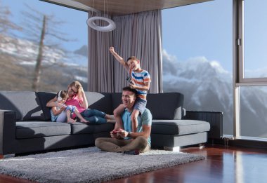 Mutlu bir aile. Baba, anne ve çocuklar video oyunu oynuyorlar. Baba ve oğul yerde oyun oynuyorlar.