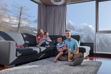 Mutlu bir aile. Baba, anne ve çocuklar video oyunu oynuyorlar. Baba ve oğul yerde oyun oynuyorlar.