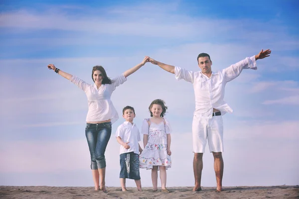幸せな若い家族はビーチで楽しみ 子供たちを保護しながら接続された手でホームサインを示す — ストック写真