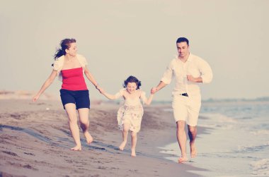 Mutlu genç aile eğleniyor ve sahilde sağlıklı bir hayat sürüyor.