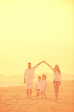 Mutlu genç aile gün batımında sahilde eğleniyor.