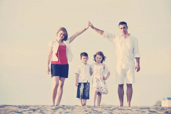 幸せな若い家族はビーチで楽しみ 子供たちを保護しながら接続された手でホームサインを示す — ストック写真
