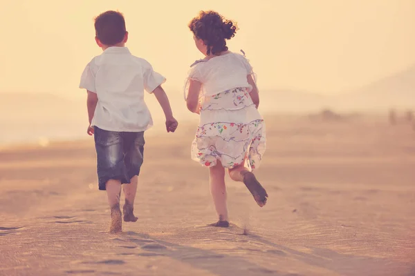 Glad ung familj ha kul på stranden vid solnedgången — Stockfoto