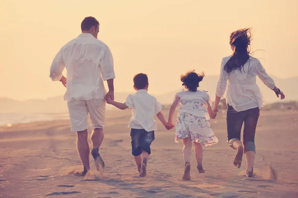 Feliz jovem família se divertir na praia ao pôr do sol — Fotografia de Stock