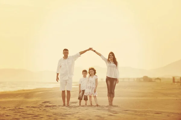 Glückliche junge Familie hat Spaß am Strand bei Sonnenuntergang — Stockfoto