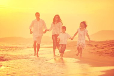 Mutlu genç aile gün batımında sahilde eğleniyor.