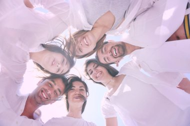 Kumsalda bir grup mutlu genç eğleniyor ve gülümsüyor.