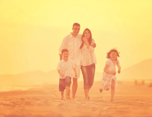 Feliz familia joven divertirse en la playa al atardecer — Foto de Stock