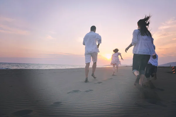 Gelukkig jong gezin veel plezier op het strand bij zonsondergang — Stockfoto