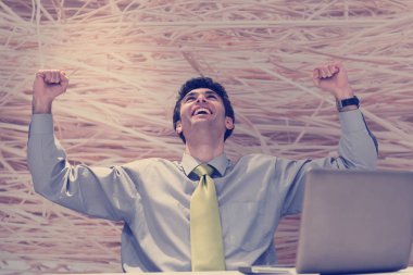 Modern ofis içindeki masasında dizüstü bilgisayarda çalışan mutlu genç iş adamı.