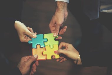İş adamları yapboz oluşturuyorlar ve takım desteği ve konsepti temsil ediyorlar, modern parlak ofis içlerinde üst görüş perspektifi