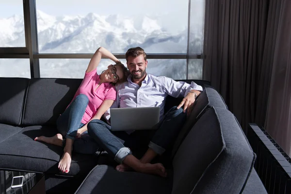 Para relaksujący w domu przy użyciu komputerów typu laptop — Zdjęcie stockowe