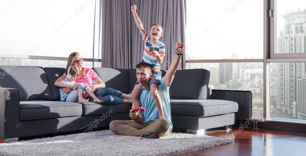 Happy family. Father, mother and children playing a video game Father and son playing video games together on the floor