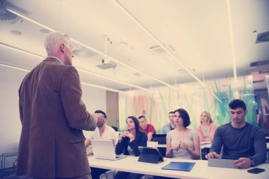 Modern okul sınıfında bir grup öğrenci profesörle birlikte çalışıyor.