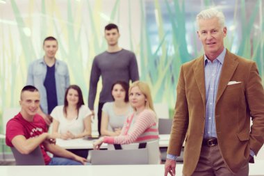 Kendine güvenen öğretmenin portresi, arka planda öğrenci grubu