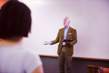 Modern okul sınıfında bir grup öğrenci profesörle birlikte çalışıyor.