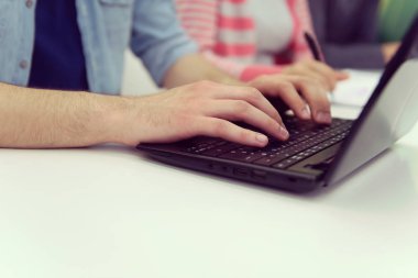 modern okul sınıfında dizüstü bilgisayara yazarak genç iş adamı öğrenci öğrenci elleri yakın, backgrond sınıf arkadaşları bulanık