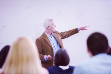 Modern okul sınıfında bir grup öğrenci profesörle birlikte çalışıyor.