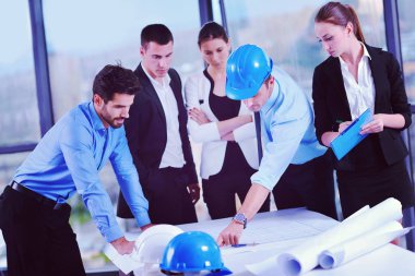 İş adamları, inşaat mühendisi mimar ve işçi görünümlü yapı modeli ve proje planlarıyla modern ofiste toplantı ve sunum üzerine bir araya geldiler.