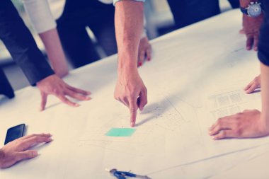 İş adamları, inşaat mühendisi mimar ve işçi görünümlü yapı modeli ve proje planlarıyla modern ofiste toplantı ve sunum üzerine bir araya geldiler.