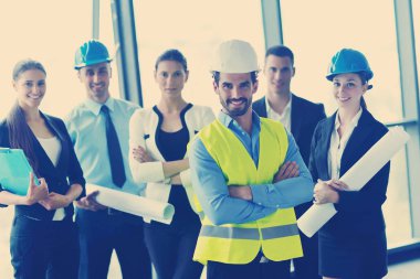 İş adamları, inşaat mühendisi mimar ve işçi görünümlü yapı modeli ve proje planlarıyla modern ofiste toplantı ve sunum üzerine bir araya geldiler.