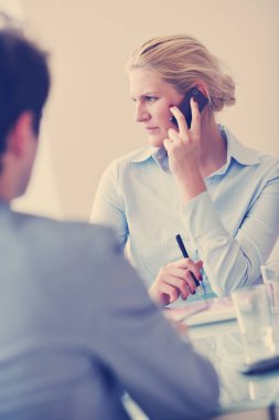 Sarışın genç iş kadını buluşmada cep telefonuyla konuşuyor.