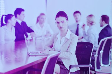 Çalışanlarıyla birlikte çalışan bir iş kadını, modern aydınlık ofiste arka planda çalışan insanlar.