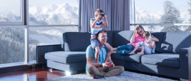 Mutlu bir aile. Baba, anne ve çocuklar video oyunu oynuyorlar. Baba ve oğul yerde oyun oynuyorlar.
