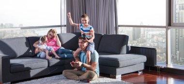Mutlu bir aile. Baba, anne ve çocuklar video oyunu oynuyorlar. Baba ve oğul yerde oyun oynuyorlar.