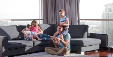Mutlu bir aile. Baba, anne ve çocuklar video oyunu oynuyorlar. Baba ve oğul yerde oyun oynuyorlar.