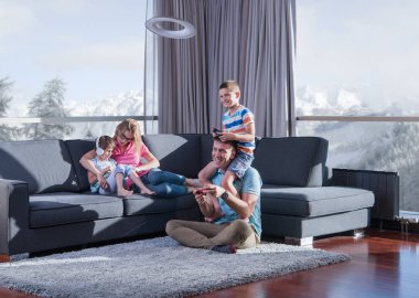 Mutlu bir aile. Baba, anne ve çocuklar video oyunu oynuyorlar. Baba ve oğul yerde oyun oynuyorlar.